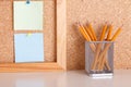 Workplace with part of wooden frame and two stickers pinted on cork board and pencils in pencil case on white table. Mock up Royalty Free Stock Photo