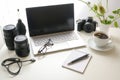 Workplace of a photographer, white office desk with laptop, camera, equipment, notepad and a cup of coffee, copy space, selected