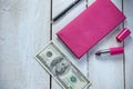 Workplace with pink leather wallet, money, pen and lipstick on white wooden table Royalty Free Stock Photo