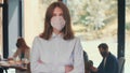 Workplace safety measures. Portrait of young happy gen-z 20s business woman wear mask at modern light office slow motion