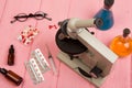 Workplace scientist doctor - microscope, pills, syringe, eyeglasses, chemical flasks with liquid on pink wooden table Royalty Free Stock Photo