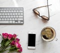 Workplace with smartphone, coffee, keyboard and roses,