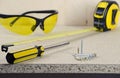 Workplace, tape measure, yellow screwdriver, glasses and screws on wooden table Royalty Free Stock Photo