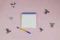 Workplace of the women`s table with metal clothespins, a pen and an open notepad on a pink background