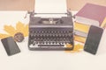 Retro and modern writer gadgets: two mobile phones, old typewriter, stack of books and yellow dry leaves
