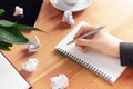 Workplace of writer, rewriter. Female hand holding pen and writing in notepad. Crumpled paper and creature process. Business Royalty Free Stock Photo