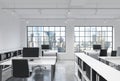 Workplaces in a bright modern loft open space office. Tables are equipped with modern computers; corporate documents' shelves. New