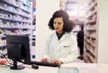 She works hard to get her customers the lowest prices. a pharmacist working on a computer in a pharmacy. Royalty Free Stock Photo