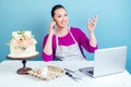 Confectioner housewife pastry-cook businesswoman talking on the phone and works with a laptop next to white two-tiered
