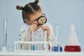 Works with test tubes. Little girl in coat playing a scientist in lab by using equipment Royalty Free Stock Photo