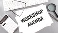 WORKSHOP AGENDA text on paper with keyboard, calculator on grey background