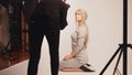 Workshop backstage - Blonde handsome girl posing for photographer - model sits at knees Royalty Free Stock Photo