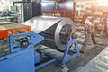 Worksop with machinery tools and equipment, rolls of galvanized steel for production metal pipes and tubes in factory