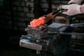 Workspace of blacksmith. Blacksmith working in gloves with red hot metal workpiece of new hammer at anvil in a forge Royalty Free Stock Photo