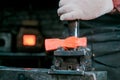 Workspace of blacksmith. Blacksmith working with red hot metal of new hammer at anvil in a forge. Making the hole Royalty Free Stock Photo