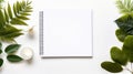 workspace with a blank notebook, green leaves, and a white container on a white background Royalty Free Stock Photo