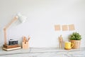 Workspace with books, camera, lamp, coffee with plant on marble desk