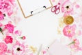 Workspace with clipboard, roses petals and accessories on white background. Flat lay, top view Royalty Free Stock Photo