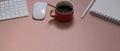 Workspace with coffee cup, stationery, keyboard, mouse and copy space on pink table Royalty Free Stock Photo