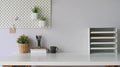 Workspace coffee cup that surrounded by document shelf, picture frame, pencils in glass vase, pine cone and notebooks.