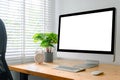 Workspace with computer with blank white screen, and office supplies on a wooden desk Royalty Free Stock Photo