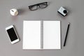Workspace desk with blank notebook, pencil, eye glasses, small action camera, piggy bank and smart phone on gray background Royalty Free Stock Photo