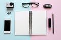 Workspace desk with blank notebook, pencil, lipstick, car key, eye glasses, small action camera, earrings and smart phone on pink Royalty Free Stock Photo