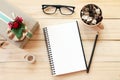 Workspace desk with notebook, pencil, pine cones in tea wooden cup, eye glasses, gift box and ribbon on wooden background Royalty Free Stock Photo