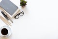 Workspace desk. Top view office desk with notebook, pencils, glasses and plant on white color background. Royalty Free Stock Photo