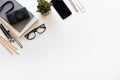 Workspace desk. Top view office desk with notebook, pencils, glasses, smartphone, camera and plant on white color background Royalty Free Stock Photo