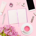 Workspace with diary, pen, smartphone, lipstick, alstroemerias, tea cup, cosmetics tube on pastel pink background. Royalty Free Stock Photo