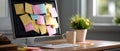 Computer monitor covered with colorful sticky notes on a wooden desk with keyboard, coffee cup, and potted plant in a bright Royalty Free Stock Photo