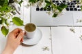 Workspace with girl`s hand on laptop keyboard and cup of coffee, white spring apple tree flowers on white woodden background. Vie Royalty Free Stock Photo