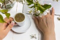 Workspace with girl`s hand on laptop keyboard and cup of coffee, white spring apple tree flowers on white woodden background. Vie Royalty Free Stock Photo