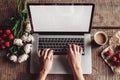 Workspace with girl`s hands, laptop computer, bouquet of peonies flowers, coffee, strawberries, smartphone on rough wooden table. Royalty Free Stock Photo