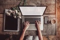 Workspace with girl`s hands, laptop computer, bouquet of peonies flowers, coffee, strawberries, smartphone on rough wooden table. Royalty Free Stock Photo