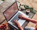 Workspace with girl`s hands, laptop computer, bouquet of peonies flowers, coffee, strawberries Royalty Free Stock Photo