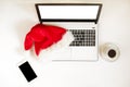 Workspace with laptop and christmas gift and santa hat on white background flat lay, top view, copy space. Royalty Free Stock Photo