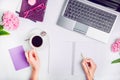 Workspace with laptop, girl`s hands writing in notebook, glasses, cup of coffee and wisteria flowers on white background. Top vie Royalty Free Stock Photo