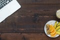 Workspace with laptop and with a healthy breakfast: mango, orange and muesli bar on wooden table. Copy space, top view