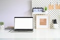 Workspace laptop, pegboard and office supplies on white table office