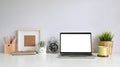 Workspace with laptop, photo frame, coffee, plant decoration, pencil.