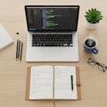 A workspace on a light wooden desk with a laptop displaying a code editor Royalty Free Stock Photo