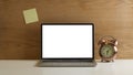 Workspace with mock up laptop, clock and sticky note on wooden wall Royalty Free Stock Photo