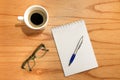 Flat desk, top view office table. Workspace with notepad, pencil, green frame glasses and coffee cup on wooden background. Royalty Free Stock Photo