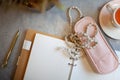 Opened notebook with clean sheets, gold pen, rosary, pink colored case and cup of tea near vase Royalty Free Stock Photo