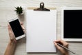 Workspace with smartphone, tablet, clipboard, female hands and pencil, overhead. Top view, from above Royalty Free Stock Photo