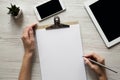 Workspace with smartphone, tablet, clipboard, female hands and pencil, overhead. Top view, from above Royalty Free Stock Photo