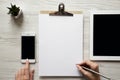 Workspace with smartphone, tablet, clipboard, female hands and pencil, top view. Overhead, from above Royalty Free Stock Photo