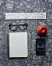 Workspace of a student engineer on a concrete surface. Loft style. Notepad, apple, calculator, pencil, glasses, ruler.